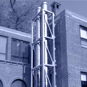 Blue tinged black & white photo of a custom chimney system built onto the side of a brick building.